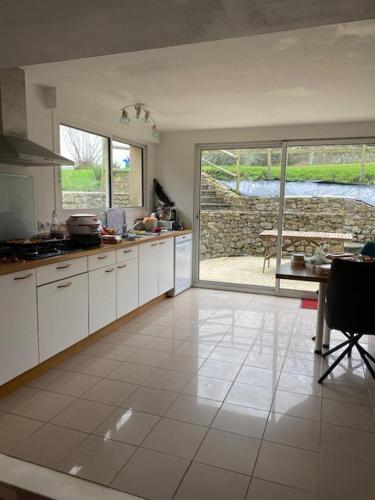 une cuisine avec des armoires blanches, une table et une fenêtre dans l'établissement Aux Dix 'Jamet, à Tourville-sur-Sienne