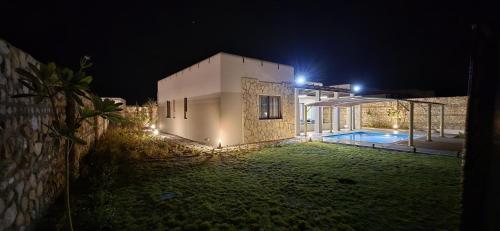 a villa with a swimming pool at night at Wateera Jebel Sifah in As Sīfah