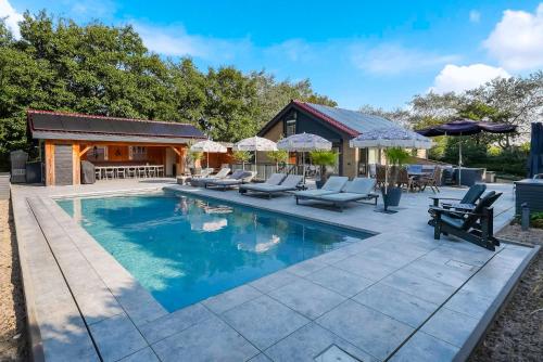 a swimming pool with chairs and a house at West Nieuwlandseweg 25A - Ouddorp - Poolvilla Zilt & Zoet in Ouddorp