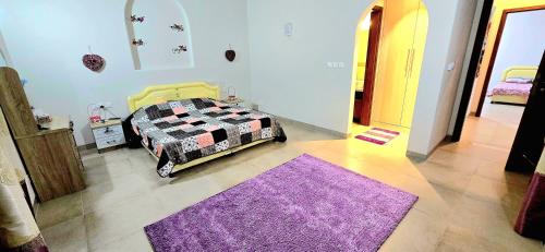 a bedroom with a bed and a purple rug at Wateera Jebel Sifah in As Sīfah