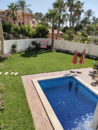 a backyard with a swimming pool and a yard with palm trees at Villa alkayan2 in fayed in ‘Ezbet el-Ibrâshi