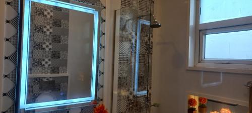 a bathroom with a shower with a mirror and a window at Oasis Suits DHA in Lahore