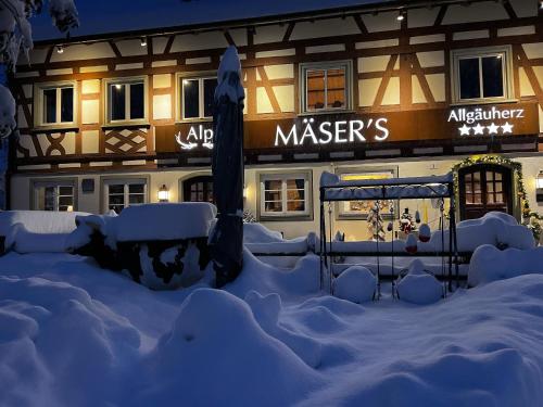 a building covered in snow in front of a building at Mäsers Allgäuherz in Wiggensbach