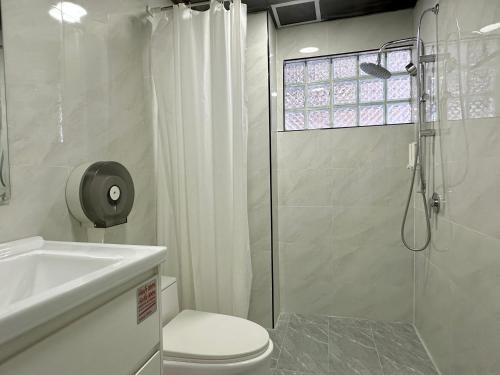 a bathroom with a shower and a toilet and a sink at Longzhu Guesthouse in Bangkok