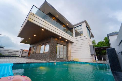 a house with a swimming pool in front of a house at Royal Cabana Lonavla - 6BHK Luxury Villa with Heated pool and Turf in Lonavala
