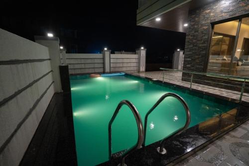 a swimming pool at night with green illumination at Royal Cabana Lonavla - 6BHK Luxury Villa with Heated pool and Turf in Lonavala