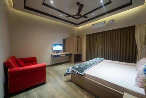 a bedroom with a bed and a red chair at Royal Cabana Lonavla - 6BHK Luxury Villa with Heated pool and Turf in Lonavala