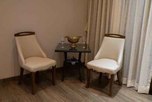 two white chairs and a table with a vase on it at Royal Cabana Lonavla - 6BHK Luxury Villa with Heated pool and Turf in Lonavala