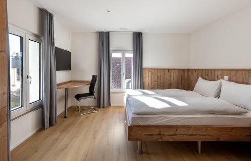 a bedroom with a bed and a desk and windows at Hotel MeiSTAY - Self-Check-in in Meisterschwanden