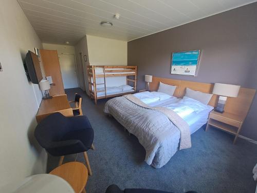 1 dormitorio con cama, escritorio y silla en Møn Golf Resort - Hotel Præstekilde, en Stege