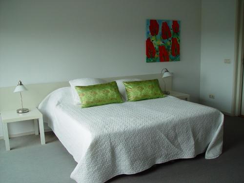 a bedroom with a white bed with two green pillows at Piaam State in Piaam