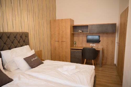 a bedroom with a bed and a desk with a television at Penzion U Nováků in Kožlí u Orlíka