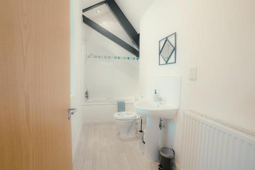 a white bathroom with a toilet and a sink at Hidden Gem in Plymouth