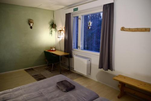 a bedroom with a bed and a desk and a window at Taigaschool Eco Hotel in Virrankylä