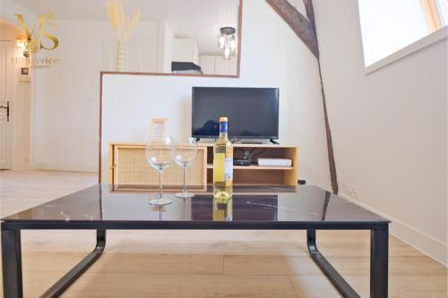 a glass table with two wine glasses and a bottle at A Corner of Paradise in Le Bugue in Le Bugue