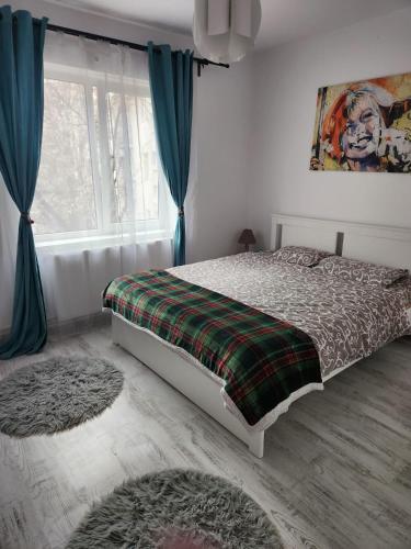 a bedroom with a bed and a window with blue curtains at ARP LUXURY Apartments in Ploieşti