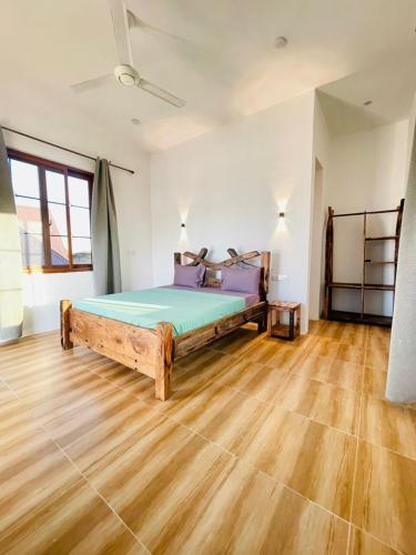 a bedroom with a bed in a room with wooden floors at Swahili lodge nungwi in Kinyasini