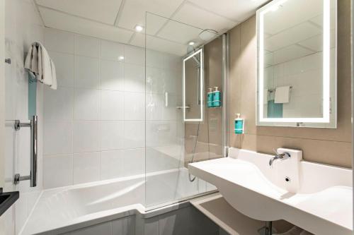 une salle de bain blanche avec une douche et un lavabo dans l'établissement Novotel Beaune, à Beaune