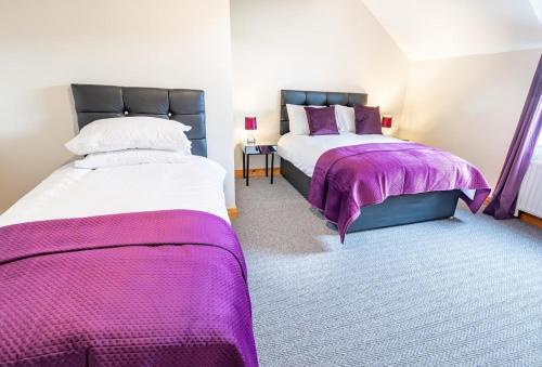 two beds in a room with purple blankets at The Townhouse Ballycastle in Ballycastle