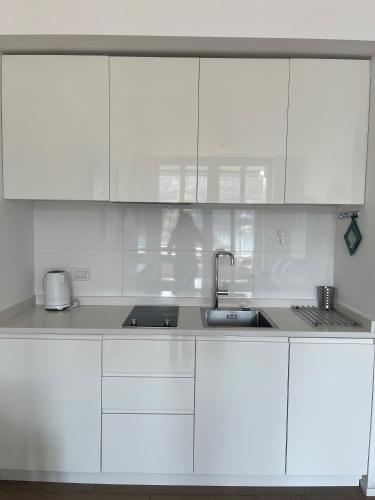a white kitchen with white cabinets and a sink at Serviced Apartments by Hotel de Charme Laveno in Laveno
