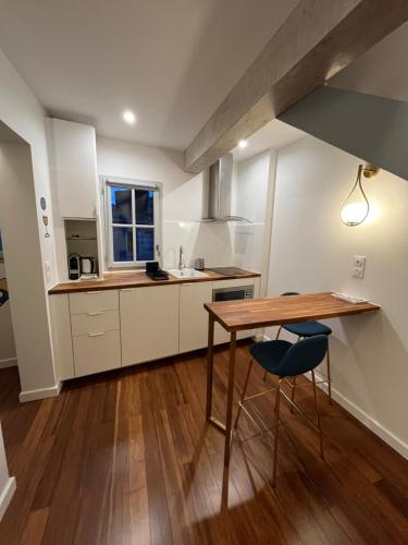 une cuisine avec des armoires blanches et une table et des chaises en bois dans l'établissement Little Lewis by Home&Art, à Montpellier