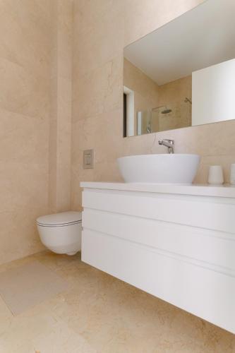a bathroom with a white sink and a toilet at Akamas Luxury Villas in Paphos