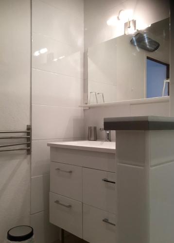 une salle de bain blanche avec un lavabo et un miroir dans l'établissement La TONNELLE, à Gailhan