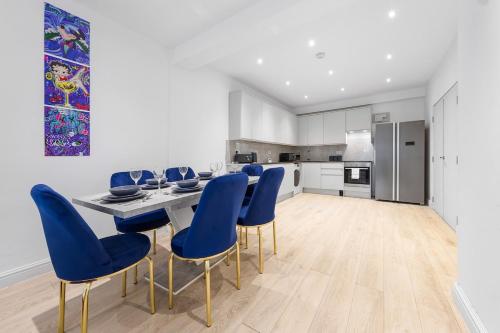 a kitchen with a dining table and blue chairs at Purple Reignz - 3BR - close to LDN in Brent Station
