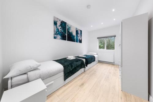 a white bedroom with two beds and a mirror at Purple Reignz - 3BR - close to LDN in Brent Station