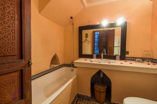 a bathroom with a sink and a tub and a mirror at Riad - Dar Al Andalous in Fès
