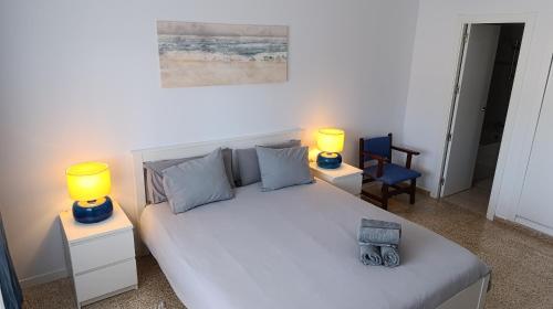 a bedroom with a large white bed with two lamps at Mountain View Apartment in Port Alcudia in Port d'Alcudia