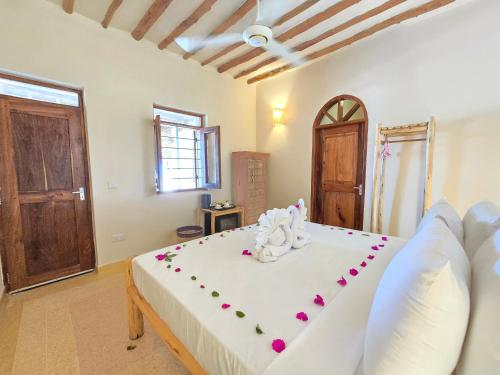 a bedroom with a large white bed with flowers on it at HA Beach Boutique - Adults Only in Jambiani