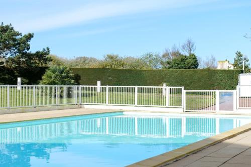 une clôture blanche autour d'une piscine d'eau bleue dans l'établissement Appartement avec piscine commune - quartier Pironnière - 4 personnes, à Les Sables-dʼOlonne