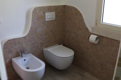 a bathroom with a white toilet and a sink at Country villa Sant' Elène- Appartamento Mirto in Orosei