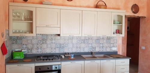 a kitchen with white cabinets and a sink at Country villa Sant' Elène- Appartamento Mirto in Orosei