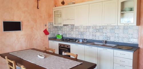 a kitchen with white cabinets and a table and a stove at Country villa Sant' Elène- Appartamento Mirto in Orosei