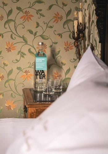 a bottle of water sitting on a table next to glasses at Hotel Flora in Venice