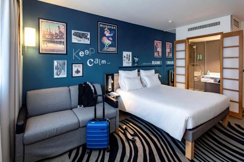 a hotel room with a bed and a couch at Novotel Beaune in Beaune