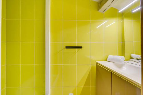La salle de bains jaune est pourvue d'une douche et d'un lavabo. dans l'établissement L'Ô en Couleur - Au coeur de Bordeaux, à Bordeaux