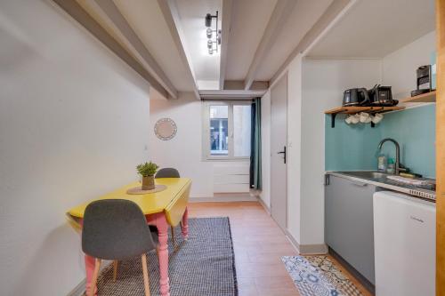 une petite cuisine avec une table et des chaises jaunes dans l'établissement L'Ô en Couleur - Au coeur de Bordeaux, à Bordeaux