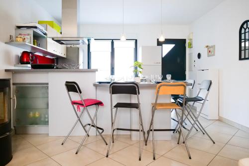 une cuisine avec quatre chaises autour d'un comptoir de cuisine dans l'établissement L'échappée sablaise - maison proche gare - 6 personnes, à Les Sables-dʼOlonne