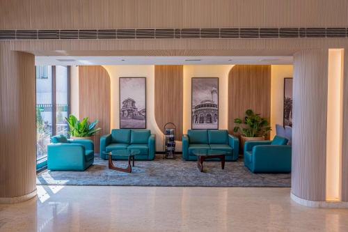 a lobby with blue couches and tables in a building at Park Inn & Suites by Radisson Bengaluru Yelahanka in Bengaluru