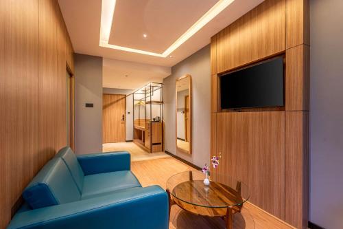 a living room with a blue couch and a television at Park Inn & Suites by Radisson Bengaluru Yelahanka in Bengaluru