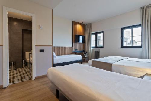 a hotel room with two beds and a desk at Hotel Acta Madfor in Madrid