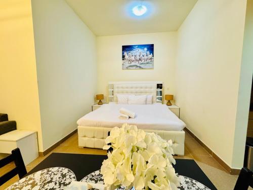 ドバイにあるPremium Large Studio in Hamilton residency business bay Marasi Drive Dubaiのベッドルーム1室(白いシーツと花のベッド付)