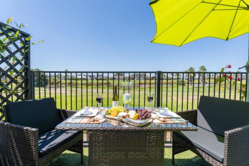 a table with a plate of fruit and an umbrella at Palm Springs Pearl - 7 minutes walk to the beach in Papamoa