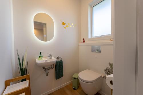a bathroom with a toilet and a sink and a mirror at Palm Springs Pearl - 7 minutes walk to the beach in Papamoa