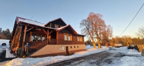 a man standing in front of a house in the snow at Švarná Hanka - turistická chata in Staré Hamry