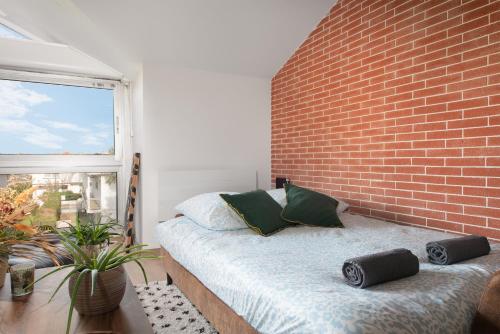 une chambre avec un mur de briques et un lit dans l'établissement Le Loft Botanique Et Son Parking Gratuit, à Toulouse