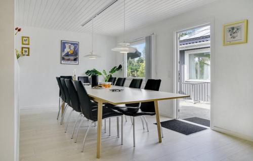 a dining room with a table and black chairs at Pool activity house for 14 people in Bøtø By